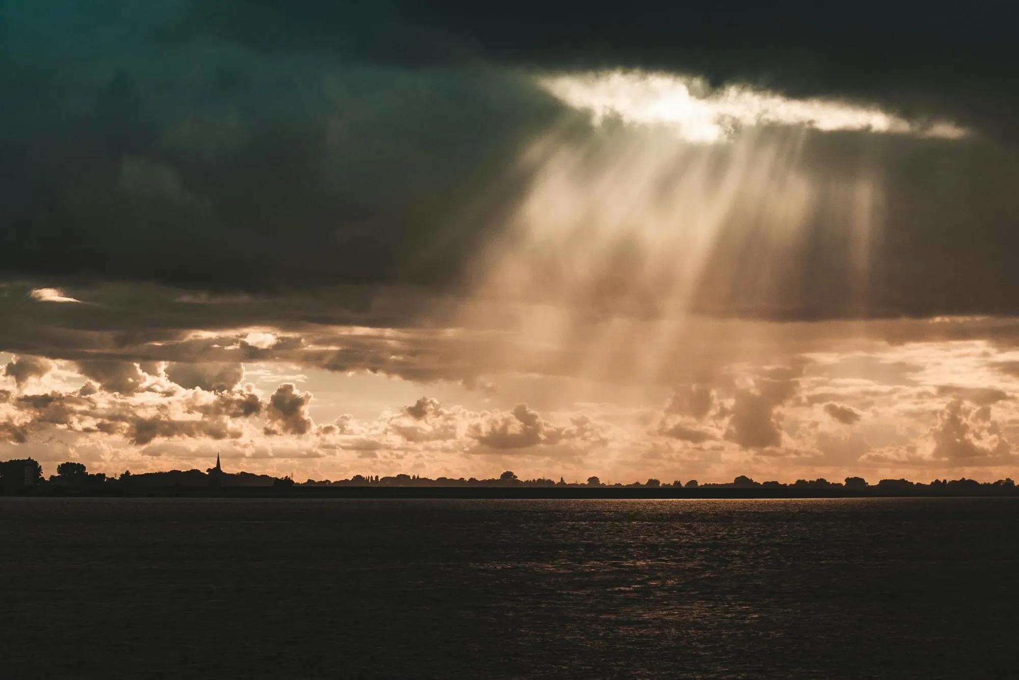 Sun rays breaking through cloud cover over water